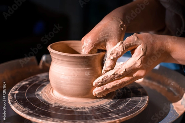 Fototapeta Potter master woman sculptor works with clay on a Potter's wheel and at the table with the tools. Close-up.