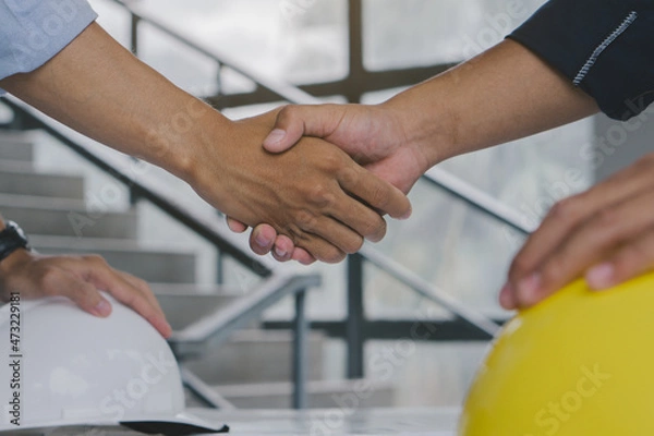 Fototapeta Architect and engineer shaking hands after finish an agreement in the office construction site, success collaboration concept.