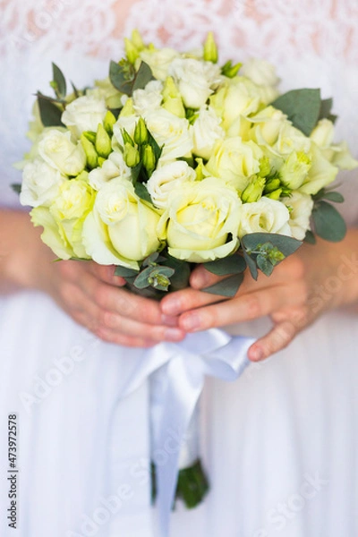 Fototapeta Wedding bouquet of pale yellow roses in bride's hands 