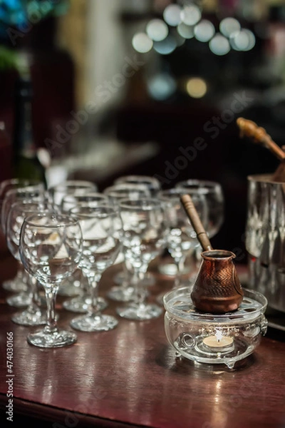 Fototapeta copper Turkish coffee cup stands on a wooden table in the bar in the evening in the semi-darkness, restaurant bar counter