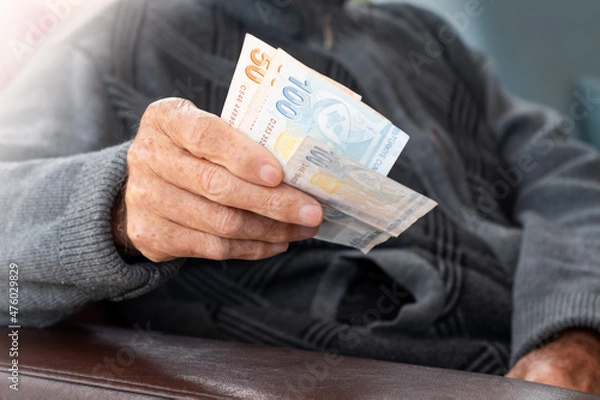 Fototapeta Senior man wrinkled hands holding Turkish Lira banknotes.Financial currency crisis concept.