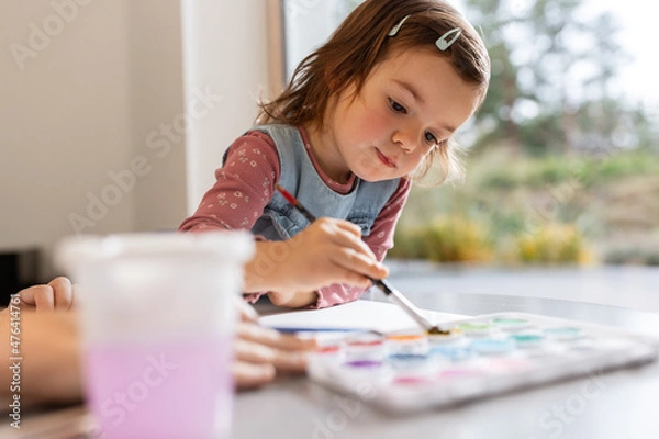 Fototapeta childhood, hobby and leisure concept - little girl drawing picture with colors and brush at home