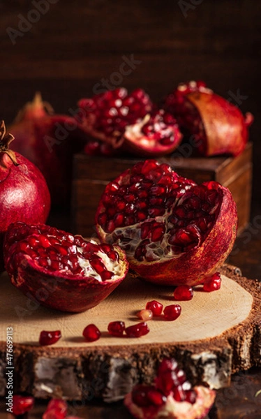 Fototapeta Red ripe pomegranates on a wooden background. The cut fruits of the pomegranate tree.