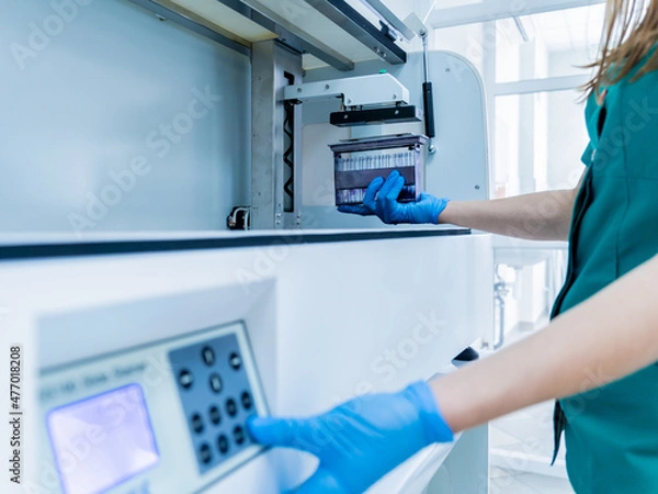 Fototapeta Laboratory assistant works with automatic multi slides stainer at the modern laboratory.