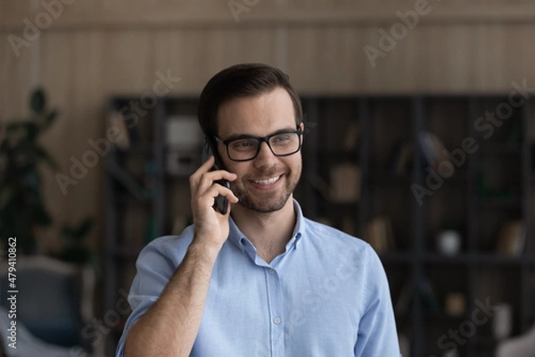 Fototapeta Head shot close up smiling man wearing glasses making or answering cellphone call, enjoying pleasant conversation with friend, friendly businessman entrepreneur consulting client by phone call