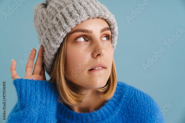 Fototapeta Young blonde woman wearing knit hat looking aside