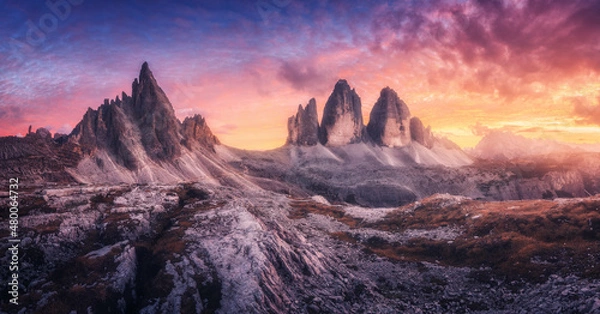 Fototapeta Mountains and beautiful sky with colorful clouds at sunset. Summer landscape with mountain peaks, stones, grass, trails, violet sky with red clouds. High rocks. Tre Cime in Dolomites, Italy. Nature