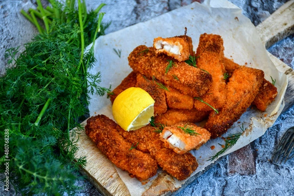 Fototapeta Close up of   Crispy breaded  deep fried fish fingers with breadcrumbs served  with remoulade sauce and  lemon Cod Fish Nuggets on rustic wood table background