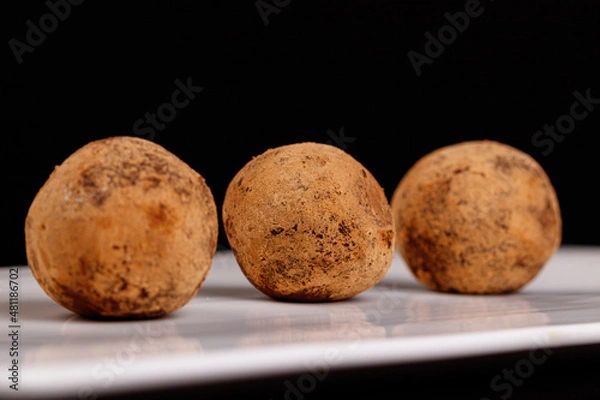 Fototapeta Beautiful candy truffle on a white plate on a black background