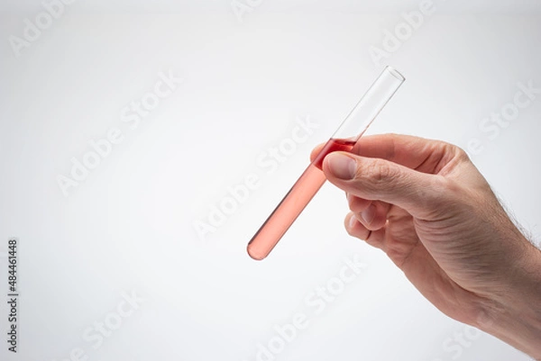 Fototapeta Medical test tube containing a light pink liquid held in hand by Caucasian male. Close up studio shot, isolated on white background