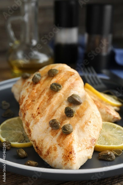 Fototapeta Delicious chicken fillets with capers and lemon on plate, closeup