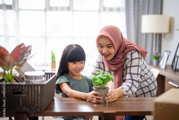 Fototapeta muslim mother and daughter decorating her house with indoor plants