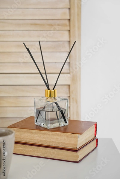 Fototapeta Aroma reed diffuser with books on table in room