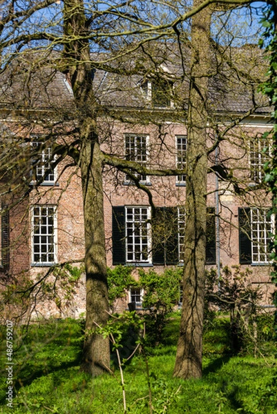 Fototapeta Dutch Mansion with shutters between trees in the sun during spring