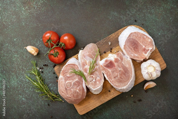 Fototapeta Fresh steaks raw turkey with rosemary and spices on a dark stone tabletop. Raw beef meat steaks for grilling. Top view flat lay background.