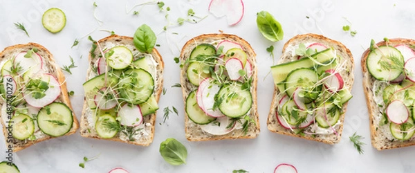 Fototapeta A row of fresh cucumber and radish tartines ready for eating.