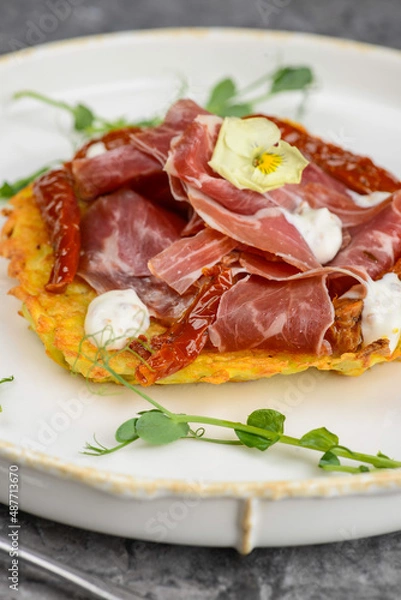 Fototapeta dish with potato and hammon pancake and dried peppers on a gray background
