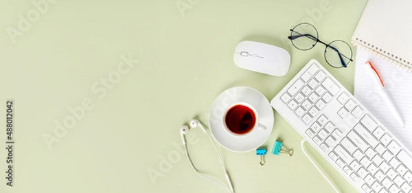 Fototapeta Light green office desk, minimalist style desk with keyboard, tea mug and glasses, copy space, top view, flat layout, layout