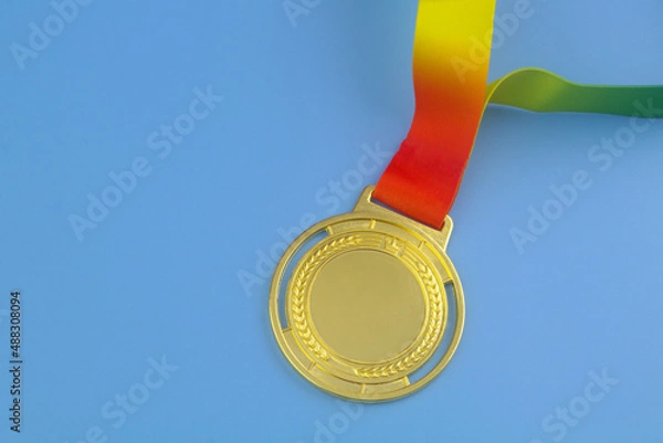 Fototapeta Gold medal with colorful ribbon on blue background