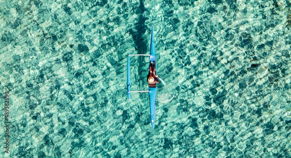 Fototapeta Un canoé polynésien navigue dans une eau turquoise d' une plage de Ramatuelle dans le Golfe de Saint-Tropez