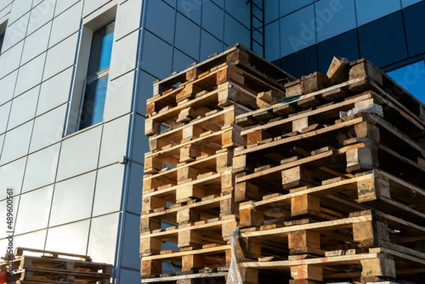 Fototapeta A stack of wooden pallets in an internal warehouse. An outdoor pallet storage area under the roof next to the store. Piles of Euro-type cargo pallets at a waste recycling facility.