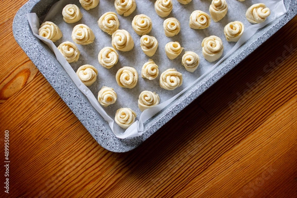 Obraz Dough for homemade cookies in a metal baking sheet. Top view. Dough for making homemade cookies. Home cooking baking cookies, buns in the form of roses, snails. The baking sheet is metallic gray.