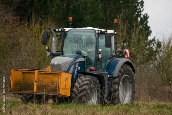 Fototapeta large farm tractor driving on a country road