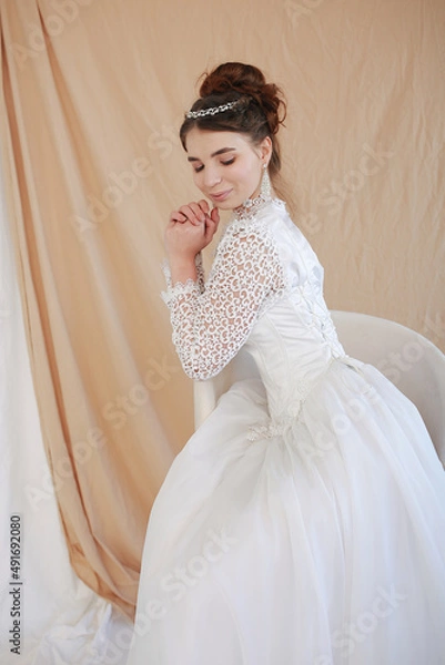 Obraz girl in a white wedding retro dress. wedding dress and hairstyle in the style of the 90's. Studio photo shoot in my mother's wedding dress. Bride photo shoot in the studio