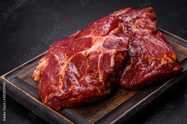 Fototapeta Raw organic marbled beef steaks with spices on a wooden cutting board