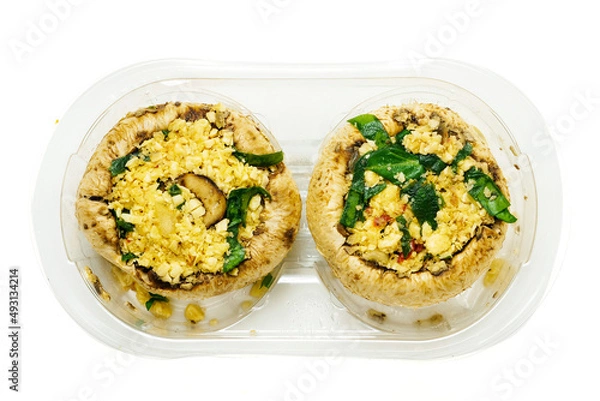 Fototapeta Two uncooked stuffed mushrooms in a plastic tray on white isolated background. Food industry product