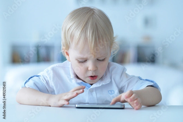 Fototapeta Portrait of boy with smartphone playing the game at home