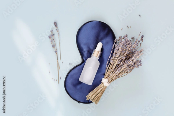 Fototapeta Relax composition with sleep mask, lavender oil and serum with lavender flowers on blue background. Lavender oil is the best natural remedy for treatment of depression, insomnia and nervous stress