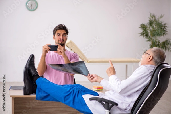 Fototapeta Young male patient visiting old male doctor radiologist