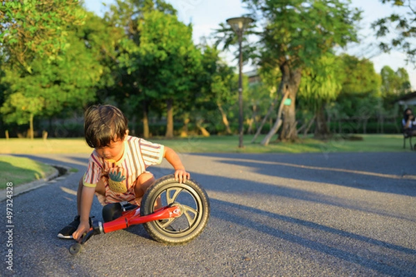 Fototapeta Asian boy about 2 years is riding baby balance bike and fall, learning concept