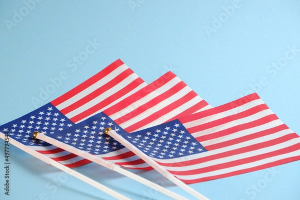 Fototapeta Three American flags on a blue background as a symbol of statehood and Independence Day on July 4th.