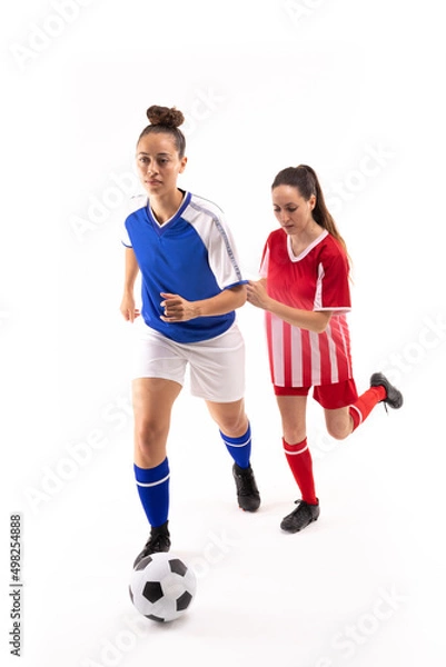 Fototapeta Full length of biracial and caucasian young female players playing soccer against white background