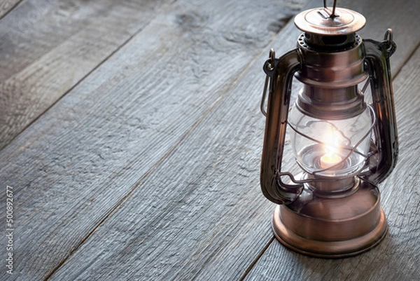 Fototapeta old kerosene lantern with burning light, antique vintage lamp on wooden table