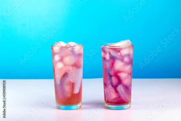 Fototapeta Summer refreshing pink cocktail with ice cube  and blackberry on blue background.