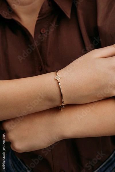 Fototapeta women's gold bracelet on the girl's hand, women's accessories, jewelry, gold bracelet with stones, women's jewelry, a girl with a bracelet on her arm, a bracelet with stones