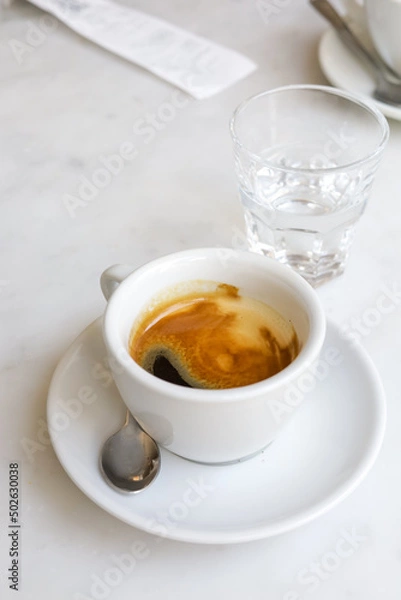 Fototapeta A cup of espresso and a glass of water after coffee.