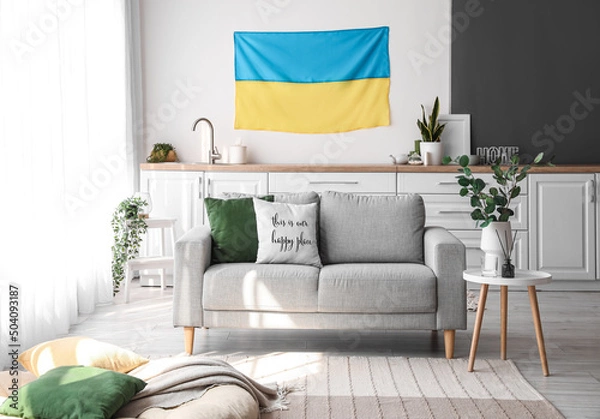 Fototapeta Interior of light kitchen with hanging Ukrainian flag, counters and sofa