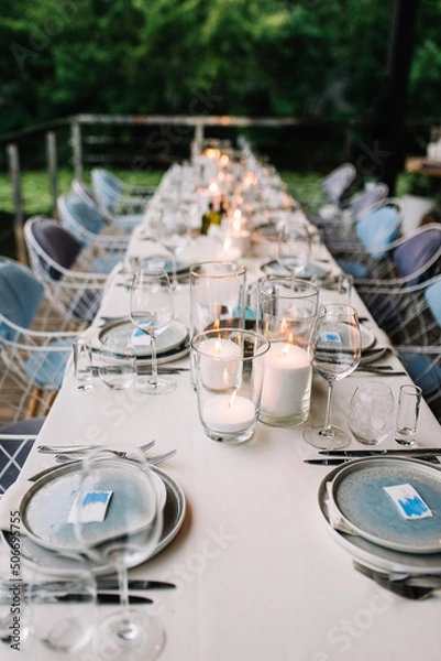 Fototapeta Wedding table serving. Wedding banquet. Beautiful festive table decorated with bouquet of flowers, black plate with card of name guest and cutlery. Top view