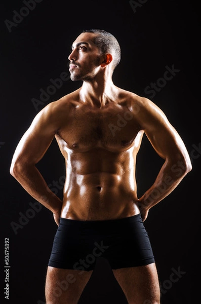 Fototapeta Muscular man in dark studio