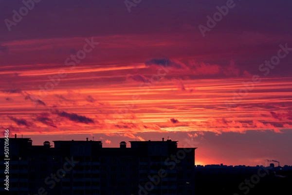 Fototapeta Stunning sunset sky over dark high-rise building silhouette. Sunset over city