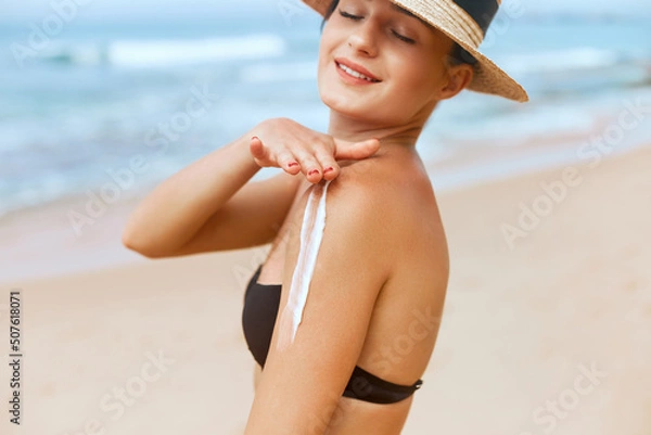 Fototapeta Beautiful Woman in Bikini Applying Sun Cream on Tanned  Shoulder. Sun Protection. Skin and Body Care. Girl Using Sunscreen to Skin