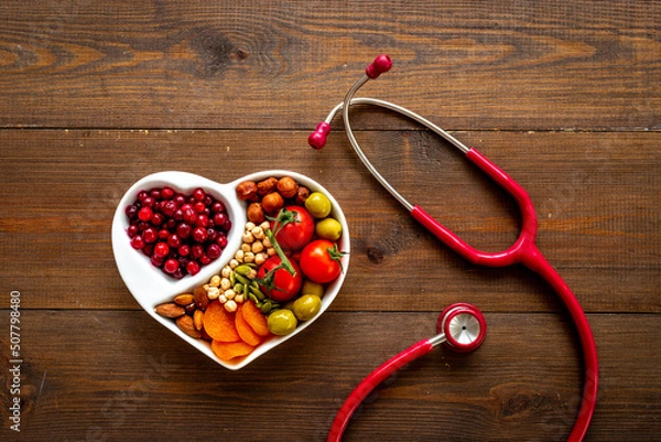 Fototapeta Healthy food in heart shaped plate with stethoscope. Healthy nutrition eating