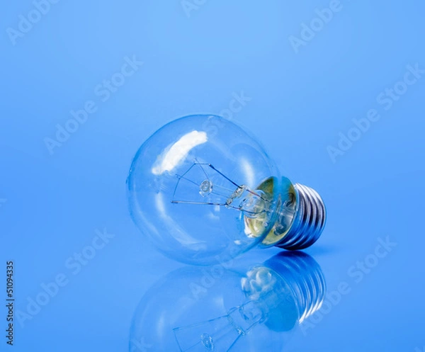 Fototapeta A light bulb, isolated on blue background