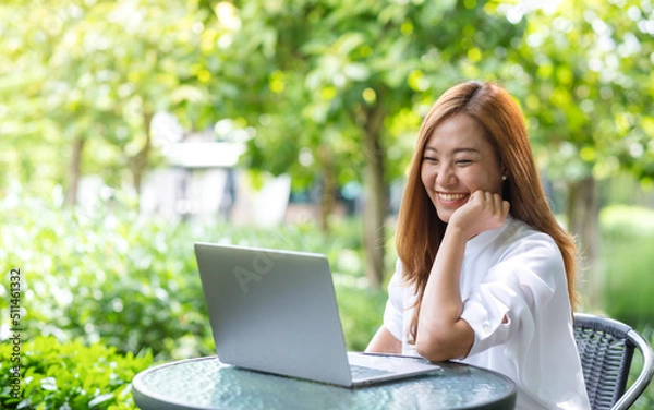 Fototapeta Portrait image of a young woman using and working on laptop computer in the outdoors