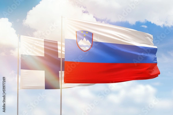 Fototapeta Sunny blue sky and flags of slovenia and finland