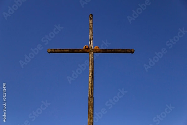 Fototapeta Dois ninhos em uma cruz de madeira com céu azul ao fundo. (Furnarius rufus)